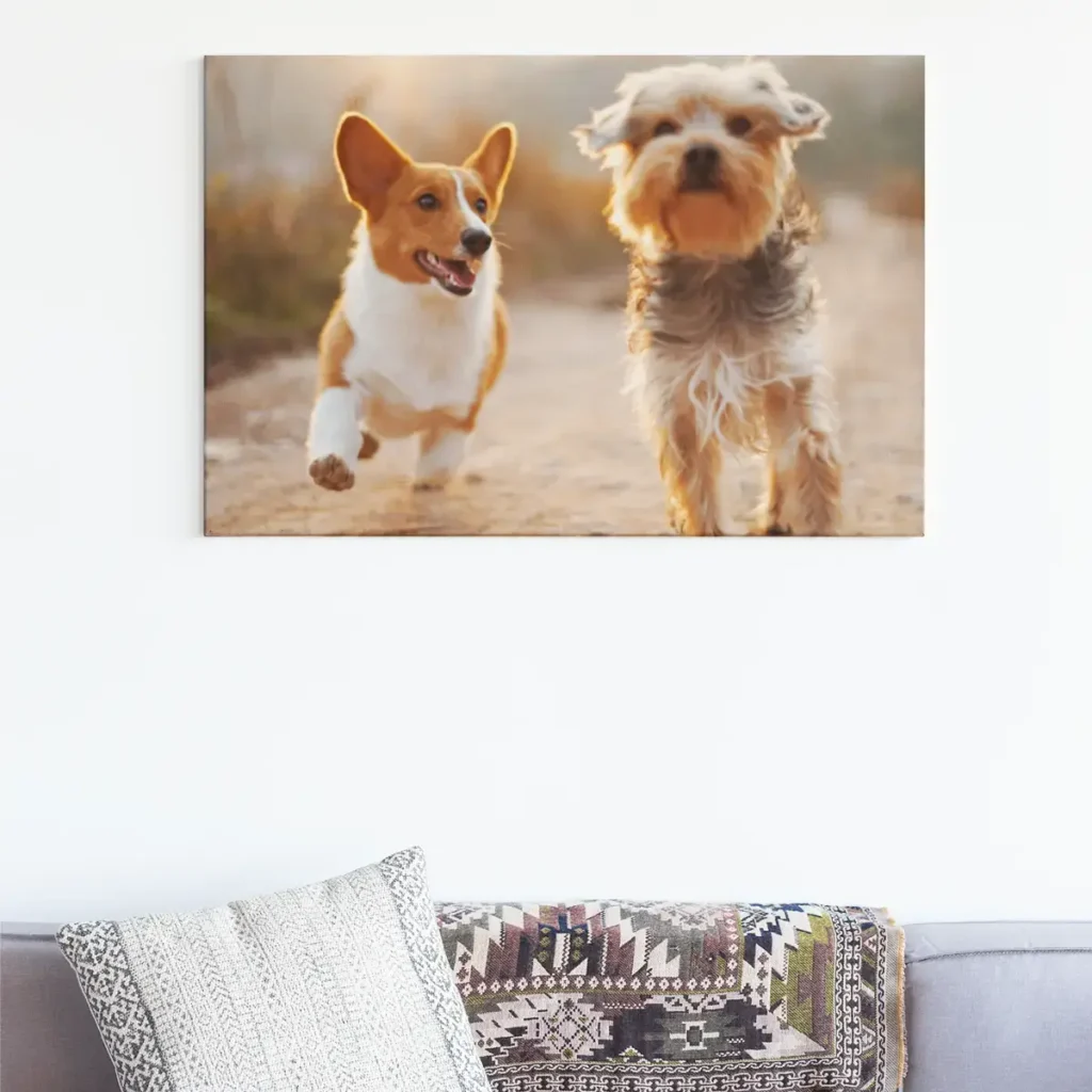 Canvas wall art of two dogs running outdoors displayed above a couch in a living room.